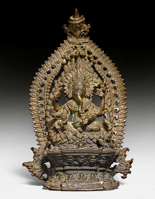 A BRONZE FIGURE OF GANESH WITH AUREOLE.
