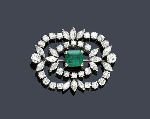 EMERALD AND DIAMOND BROOCH, ca. 1950. White gold 750. Classic-elegant brooch with a rounded rectangular shape, the middle set with 1 fine, step-cut, Columbian emerald of ca. 1.30 ct, within a border of 16 navette-cut diamonds weighing ca. 3.20 ct and 28 brilliant-cut diamonds weighing ca. 4.00 ct. Ca. 4.2 x 3.3 cm.