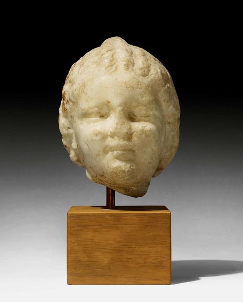MARBLE HEAD OF A CHILD,early Roman Imperial Period, Rome, 1st century A.D. Light marble. Mounted on a wooden plinth. H 15 cm. H with plinth 24 cm.
