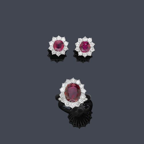 RUBY AND DIAMOND RING WITH EAR CLIPS, ca. 1950. White gold 750. Classic-elegant ring, the top set with 1 oval ruby of ca. 4.00 ct  surrounded by 14 brilliant-cut diamonds weighing ca. 1.00 ct. Size ca. 52. Matching ear clips with studs, each set with 1 round ruby weighing ca. 1.50 ct within a border of brilliant-cut diamonds weighing ca. 1.00 ct.