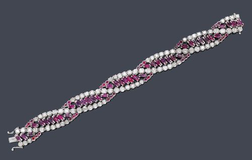 RUBY AND DIAMOND BRACELET, ca. 1950. White gold 750. Classic-elegant bracelet with stylized, interlinked band motifs, set throughout with 42 navette-cut rubies and 36 round rubies weighing ca. 3.50 ct and 84 brilliant-cut diamonds weighing ca. 5.00 ct. L ca. 18 cm.
