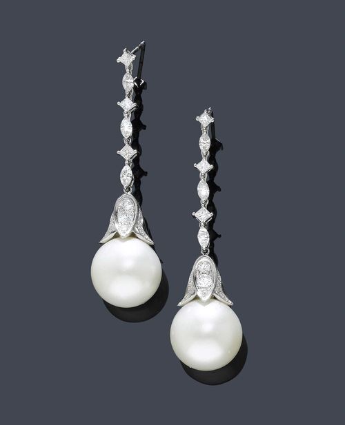 PEARL AND DIAMOND EAR PENDANTS. White gold 750. Attractive ear pendants with studs, each of a line of 3 square-cut diamonds, alternately set with 3 navette-cut diamonds. Clasp of 1 South Sea cultured pearl of ca. 16 and 15.6 mm Ø, respectively, in a calyx-shaped mounting set with brilliant-cut diamonds. Additionally decorated with small brilliant-cut diamonds. Total diamond weight ca. 2.00 ct. L ca. 5.8 cm.