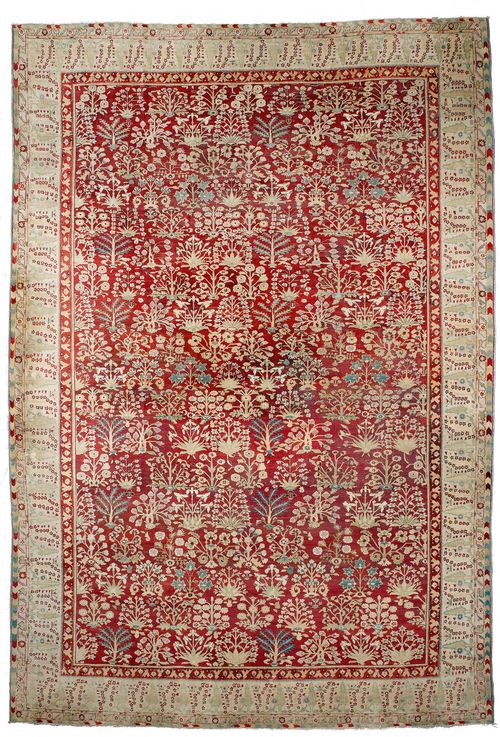 AGRA antique.Red ground, patterned throughout with plant motifs in green and white, light green edging with trees, signs of wear, 360x515 cm.