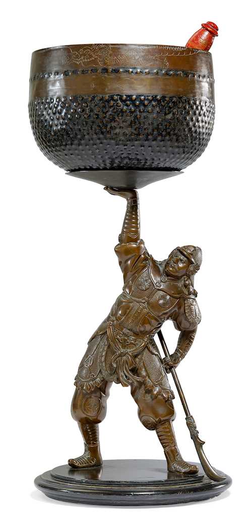 A FIGURE OF A GUARDIAN HOLDING A SINGING BOWL.