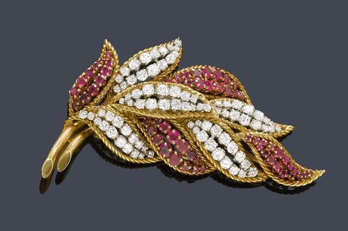 RUBY AND DIAMOND CLIP BROOCH WITH EARRINGS, ca. 1960. Yellow gold and platinum. Classic-elegant brooch designed as a stylized leaf, set throughout with ca. 83 brilliant-cut diamonds weighing ca. 3.50 ct and ca. 58 rubies weighing ca. 2.50 ct. Ca. 8 x 3.5 cm. Matching ear clips set throughout with 30 rubies weighing ca. ca. 1.00 ct and 36 brilliant-cut diamonds weighing ca. 3.00 ct.