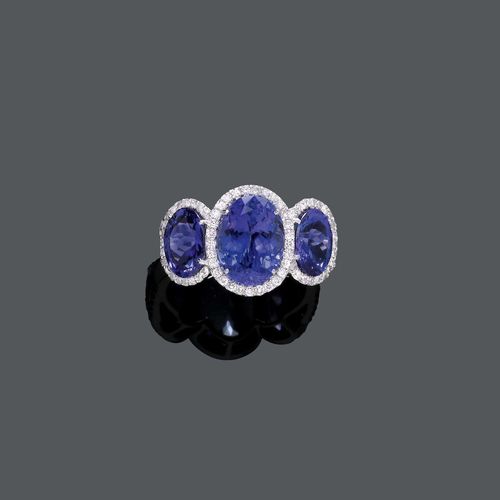 TANZANITE AND DIAMOND RING. White gold 750. Decorative, elegant ring, the top set with 3 oval tanzanites weighing ca. 6.90 ct, within a border of brilliant-cut diamonds weighing ca. 0.60 ct. Size ca. 53.