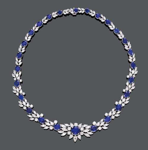 SAPPHIRE AND DIAMOND NECKLACE. White gold 750, 85g. Classic-elegant necklace set with 26 oval sapphires weighing ca. 37.30 ct, the centre diamond weighing 3.54 ct, within a border of 15 drop-cut diamonds, 108 navette-cut diamonds and 25 brilliant-cut diamonds weighing 19.50 ct in total. L ca. 41.5 cm. With GII-Report No. 1202166-002, and 13000609-002 for 2 sapphires, September 2012 and July 2013.
