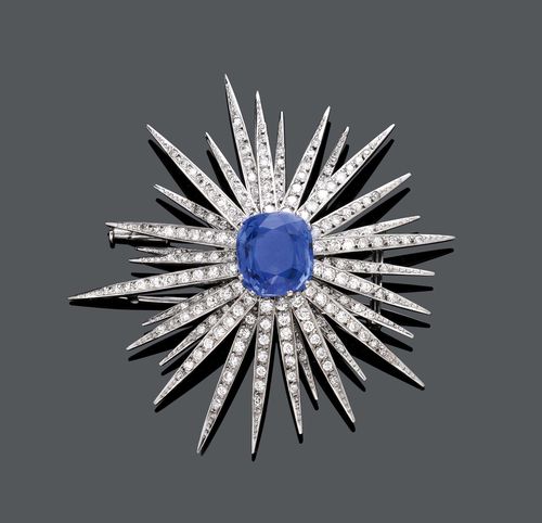 BURMA SAPPHIRE AND DIAMOND CLIP BROOCH, IGOR FABERGÉ, ca. 1950. White gold 750. Fancy, star-shaped brooch, the centre set with 1 antique-oval, fine Burma sapphire weighing ca. 11.00 ct, unheated, minimal signs of wear, the 30 rays set throughout with numerous brilliant-cut diamonds and single-cut diamonds weighing ca. 3.00 ct in total. Ca. 6.3 x 6 cm. Oral short report by GGTL/Gemlab.