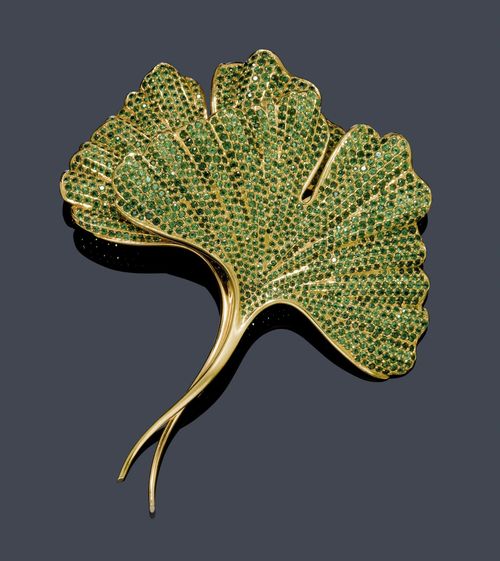 TSAVORITE AND GOLD BROOCH, HEMMERLE. Yellow gold 750, 72g. Very decorative, large brooch designed as a sculptured gingko leaf set throughout with numerous tsavorites weighing ca. 15.00 ct. Ca. 9.5 x 8.6 cm. With original case.