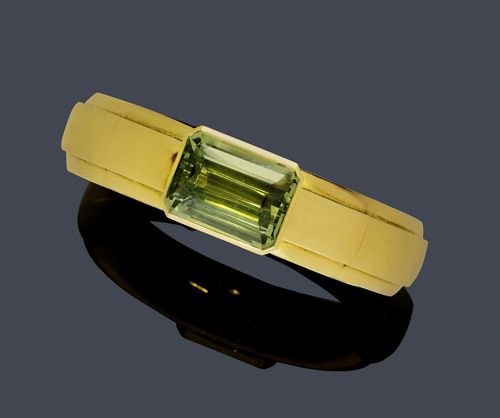 BERYL AND GOLD BANGLE, HEMMERLE. Yellow gold 750, 190g. Casual-elegant, solid bangle with 2 hinges, the front set with 1 step-cut, green beryl of ca. 30.00 ct in a collet setting. Ca. 6.2 x 5.5 cm. With original case.