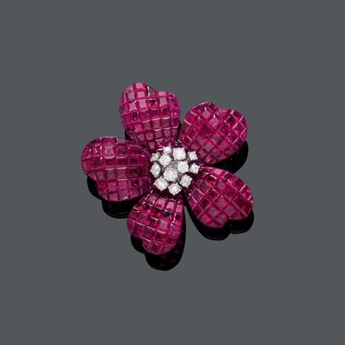 RUBY AND DIAMOND CLIP BROOCH. White gold 750. Decorative, elegant blossom-shaped clip brooch, the centre decorated with 12 brilliant-cut diamonds weighing ca. 0.90 ct, the petals set throughout with fine, princess-cut rubies, invisible setting, weighing ca. 37.00 ct. Ca. 4.4 x 4 cm.