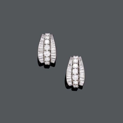 DIAMOND EAR CLIPS, ca. 1960. Platinum 950 and white gold 375, 20g. Very fancy half-Creole ear clips with studs, each with the centreline set with 8 brilliant-cut diamonds, weighing ca. 4.50 ct in total, and flanked by numerous baguette-cut diamonds, weighing ca. 4.70 ct in total.