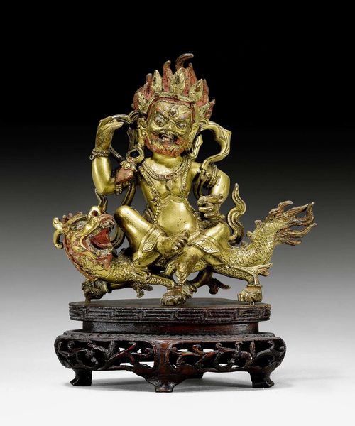 A GILT BRONZE FIGURE OF SITAJAMBHALA RIDING A DRAGON. Tibeto-chinese, 19th c. Height 10.5 cm. Wood stand later added.
