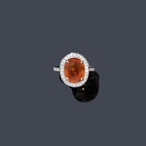 SPESSARTINE AND DIAMOND RING. White gold 750. Classic-elegant ring, the top set with 1 fine, orange, oval spessartine garnet weighing 10.40 ct, within a border of numerous brilliant-cut diamonds. Diamond-set ring shoulders. Total weight of the brilliant-cut diamonds ca. 0.60 ct. Size ca. 55. With AIGS Report No. GF12080246, August 2012.