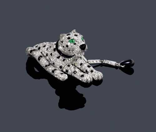 DIAMOND, ONYX AND EMERALD &quot;PANTH&#200;RE&quot; CLIP BROOCH, CARTIER, ca. 1980. Platinum 950. Ref. Q9447. Very fancy clip brooch designed  as a reclining panther with flexible paws, tail and leash set throughout with numerous brilliant-cut diamonds weighing ca. 10.00 ct. The spots, the muzzle, the collar and the leash in white gold, set with cut onyx cabochons, the eyes set with 2 drop-cut emeralds. Frame, leash and mechanical part in white gold 750. Signed Cartier Paris, No. 109637.