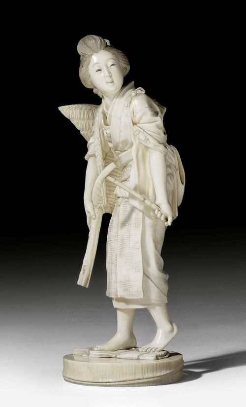 AN IVORY OKIMONO OF A WOMAN WITH SICKLE AND CARRIER. Japan, Meiji period, height 27.5 cm. Signed. Minor restoration, one chip.