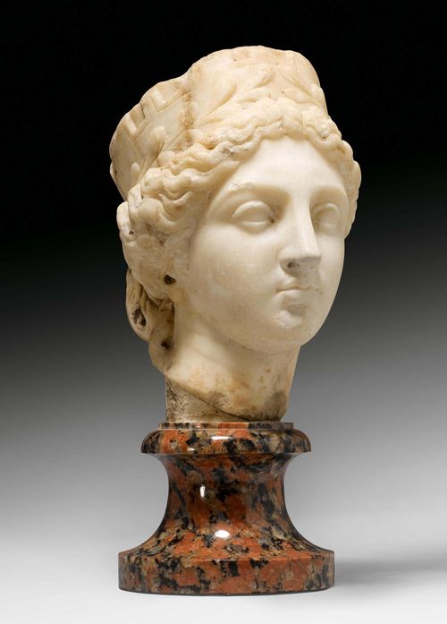 HEAD OF FORTUNA, Roman, after the Tyche of Antioch, Southern Italy, 1st century BC. Beige marble and black/grey/red granite. Fortuna with wreath and crown, mounted on a conical round base. Nose restored in the 19th century. Head: H 17.5 cm. With base: H 26 cm. Provenance: - in a Swiss private collection since 1974. A notarized document is available at Galerie Koller. With opinion by Dr. J.D. Chamay, Geneva, 15 June 2014.