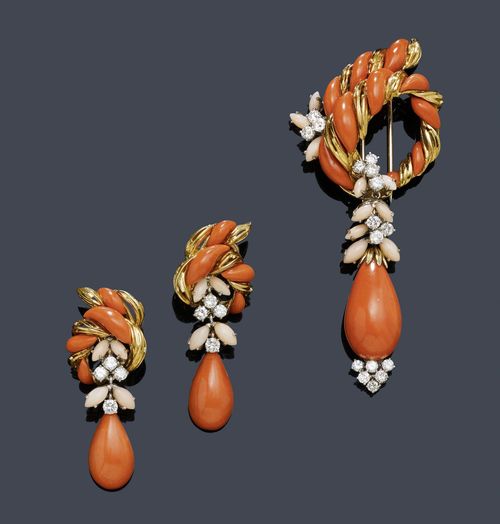 CORAL AND DIAMOND CLIP BROOCH WITH EAR PENDANTS, KUTCHINSKY, ca. 1960. Yellow and white gold 750. Very decorative brooch designed as a scrolled bank with 10 salmon pink cut corals and ribbed gold, additionally decorated with 2 blossom motifs with 3 and 2 light pink navette-cut corals, respectively. The lower part: Removable pendant with 1 salmon pink drop-cut coral of ca. 25 x 14.4 mm, 5 light pink navette-cut corals and 9 brilliant-cut diamonds. L ca. 9.5 cm. Matching ear clips, each with 4 salmon pink, 4 light pink and 1 drop-shaped coral of 20 x 11 mm as well as 4 brilliant-cut diamonds. Total weight of the brilliant-cut diamonds ca. 3.50 ct. With original case.