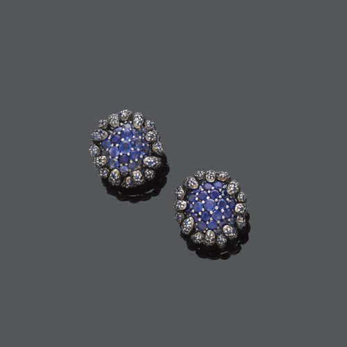 SAPPHIRE  FLOWER EARCLIPS. White gold 750 and silver. Each set with 30 sapphires, totalling ca. 9.00 ct, the petals also set with small sapphires, weighing ca. 2.00 ct, in silver mounting. Ca. 2,7 cm Ø.