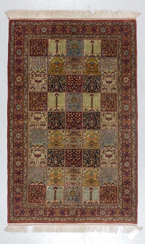 GHOM SILK, GARDEN CARPET.Central field divided into squares with plant motifs, red border with trailing flowers, in good condition, 129x205cm.
