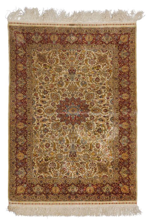 HEREKE SILK.Fineness 14x14 knots/cm2. White central field with a central medallion, finely patterned with trailing flowers and palmettes in harmonious colours, red border, in good condition, 94x126cm.