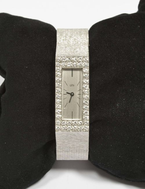 DIAMOND LADY'S WRISTWATCH, UTI, ca. 1960. White gold 750, 60g. Rectangular case integrated in the band, lunette pavé-set with 44 brilliant-cut diamonds weighing ca. 1.30 ct. Silver-coloured dial with black indices and hands, signed UTI. Hand winder, form movement Cal. FHF59-21, signed Ebel Watch. Finely textured Milanaise band, L ca. 18.5 cm. D 33 x 15 mm.