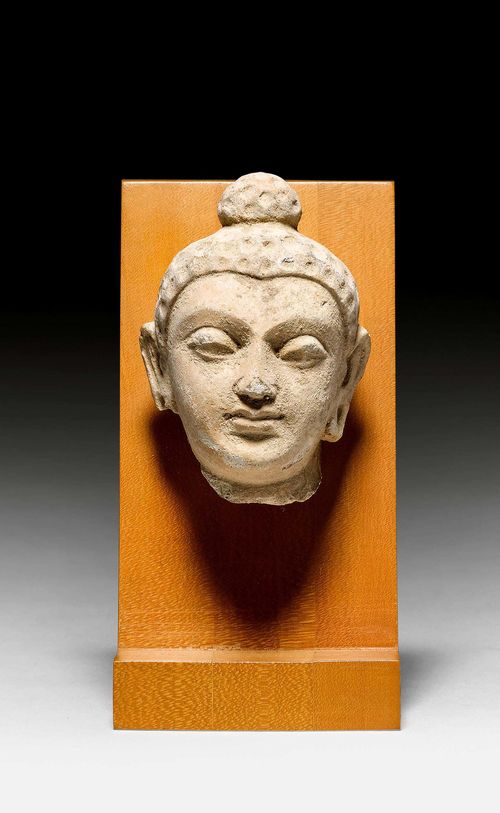 A SMALL STUCCO HEAD OF A BUDDHA. Gandhara, 4th/5th c. H 9 cm. Remains of polychromy. Mounted on a woodstand. Minor chips.