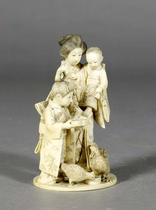 AN IVORY OKIMONO OF A LADY HOLDING A LITTLE BOY AND A GIRL FEEDING  THEIR CHICKENS. Japan, Meiji period, height 12.5 cm. Signed. Cock broken off.