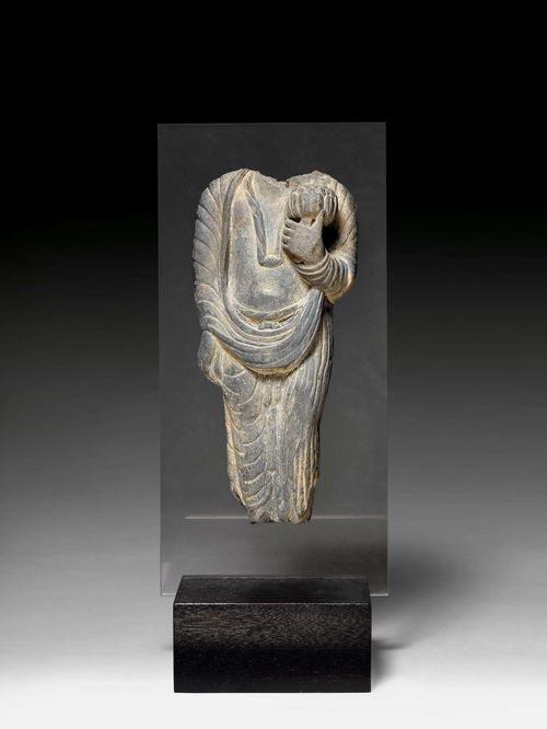 A GREY SCHIST TORSO OF A BODHISATTVA HOLDING A LOTUS. Gandhara, 4th c. H 32 cm. Woodstand with plexiglass. Slightly retouched.
