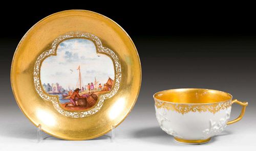 CUP AND SAUCER WITH FLORAL RELIEF AND MERCHANT SCENES, Meissen, circa 1740.With gold border and background. Underglaze blue sword marks.