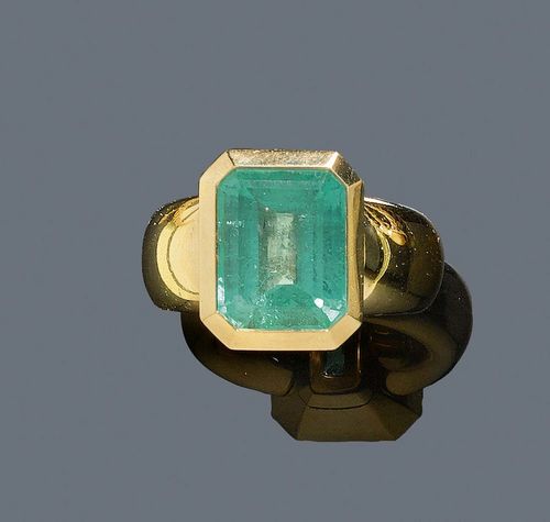 EMERALD AND GOLD RING. Yellow gold 750, 41g. Highly decorative, solid band ring, the top set with 1 large collet-set step-cut emerald of ca. 8.10 ct, treated, slight signs of wear.