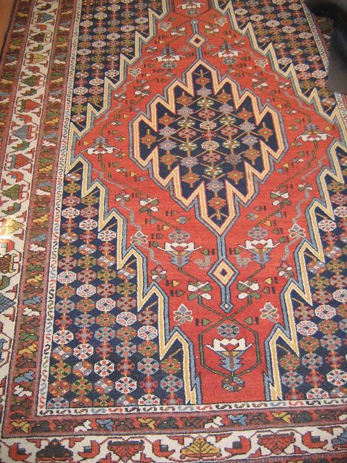 BACHTIAR old.Dark central field with a red and blue central medallion, patterned with stylized floral motifs, white border, slight wear, 195x135 cm.