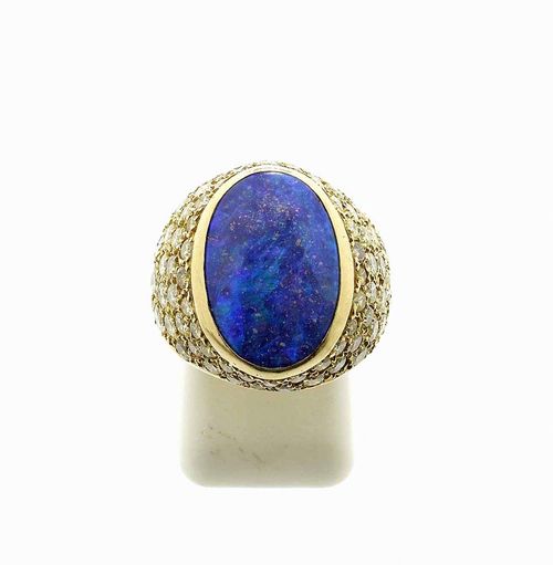 OPAL AND BRILLIANT-CUT DIAMOND RING, GRIMA, London 1975. Yellow gold 750, 13g. Elegant mantle ring, set with 1 blue Boulder opal of ca. 16 x 11 mm, the setting and the ring shoulders set with ca. 70 white and fancy yellow brilliant-cut diamonds, totalling ca. 2.00 ct. Size ca. 52, adjustable to size.