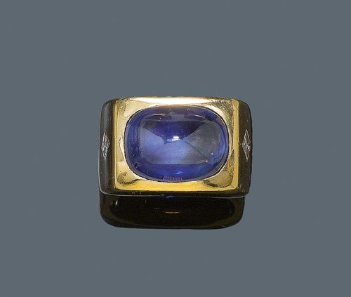 SAPPHIRE AND DIAMOND RING. Yellow gold ca. 720, 47g. Fancy, solid mantle ring, the rectangular top set with a fine Ceylon sapphire cabochon of ca. 20.00 ct, the ring shoulders additionally decorated with 2 square-cut diamonds weighing ca. 0.80 ct. Size 58, includes size adjustment insert in white gold. Tested by Gemlab. From the heirs of Baron Anton Kiss (1880-1970), son of Katharina Schratt, Schloss Mondsee.