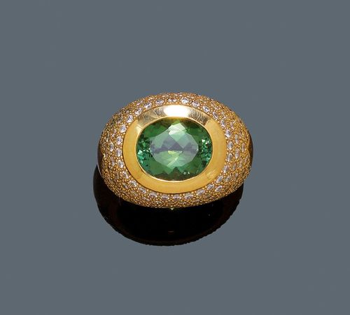 TOURMALINE AND DIAMOND RING. Yellow gold 750, 25g. Casual-elegant, solid ring. The convex top decorated with 1 oval tourmaline of ca. 6.00 ct and of fine colour, set throughout with 124 brilliant-cut diamonds weighing ca. 2.50 ct. Size 54. From the estate of Charlotte and Egon Karter-Sender, Basel.