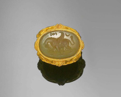 AGATE AND GOLD RING, ca. 1940. Yellow gold 916. Fancy mantle ring in Persian style, the top with an agate engraved with horse motif, the shoulders adorned with lion motifs. Size ca. 53.