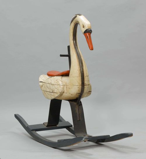 ROCKING SWAN,France, ca. 1880. Wood, carved and painted, in part reinforced with metal bands. Cream-coloured body, seat and beak painted red. On a rounded wooden stand. H 98 cm. Probably from a carousel.