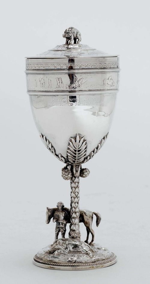 MINIATURE OF THE SO-CALLED "NAGPUR HUNT CUP",Birmingham 1911/12. Elkington & Co. Round foot with a scenic depiction of a hunter. Shaft designed as a palm tree. Cup, smooth-walled . Cover with wild boar finial. H ca. 21 cm, 400g. The original Nagpur Hunt Cup is part of the Collection of the Victoria & Albert Museums in London.