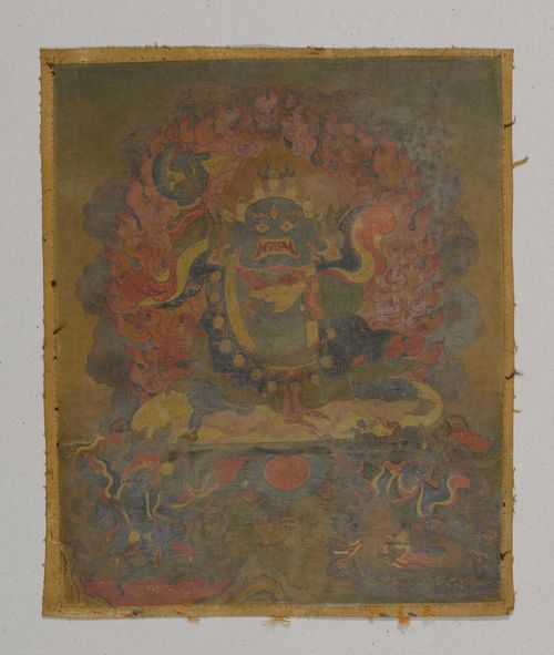 TANGKA OF A WRATHFUL DEITY.Tibet, 18th c. 32x26.5 cm. The Blue God wearing the adornments of a Dharmapala holds a skull cup and chopper, two mounted protective deities accompany him, among them Lhamo, riding a mule through a sea of blood. Colours slightly faded.