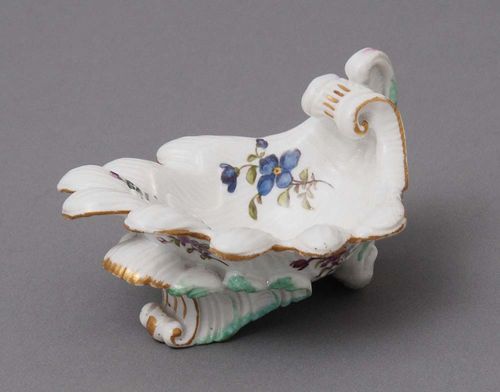 SHELL-SHAPED SALIERE, Meissen, mid-18th century.Ribbed shell shape with wavy edge and on Rocaille feet, heightened in teal and gold and painted with small bouquets of 'Deutscher Blumen'. Underglaze blue sword mark. D 10.5cm.