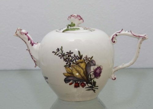 TEAPOT AND LID, Meissen, circa 1745.Oval shape with Rocaille handle, heightened in purple, painted with Holzschnittblumen, the flat lid with floral finial. H 12cm. Spout and edge of teapot slightly chipped.
