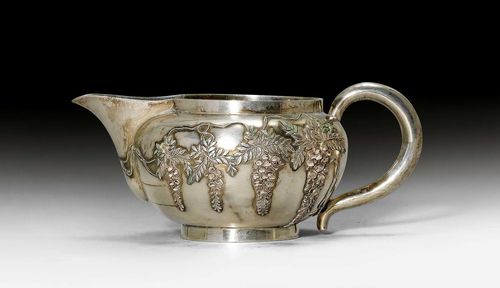 SILVER CREAMER.Japan, Meiji, L 15.5 cm, 176 g. Elegant, decoration in low relief of wisteria partly painted with enamel. Jungin mark.
