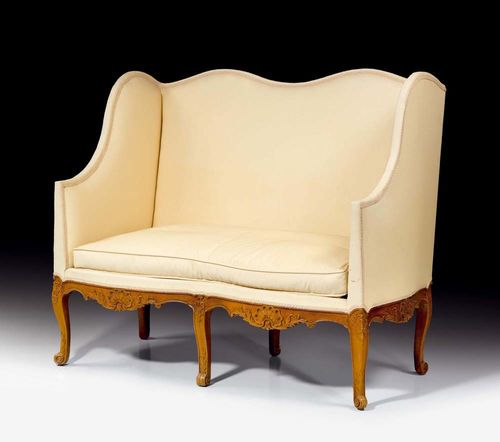 SMALL WING BACK CANAPÉ, Régence, Paris circa 1730. Finely carved beech with shells and cartouches. With beige fabric covers and cushion. 130x57x49x114 cm. Provenance: Château de Vincy, West Switzerland.