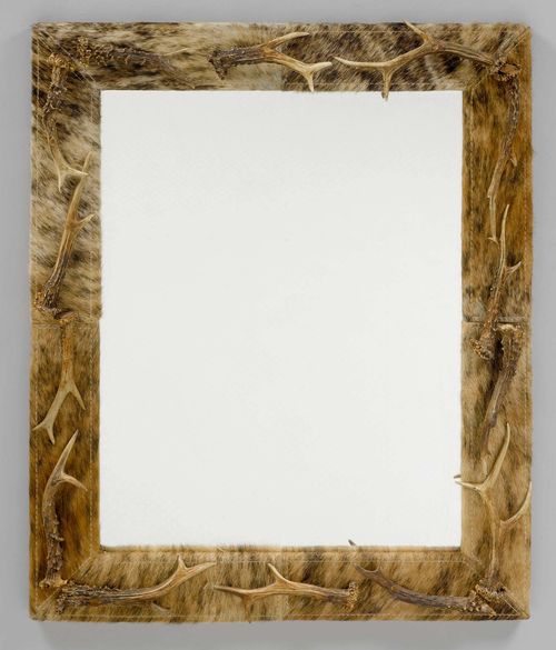 MIRROR DECORATED WITH COW HIDE AND ANTLERS, in the style of the Alpine region. Wood lined with cow hide and decorated with antlers. 88x72 cm.