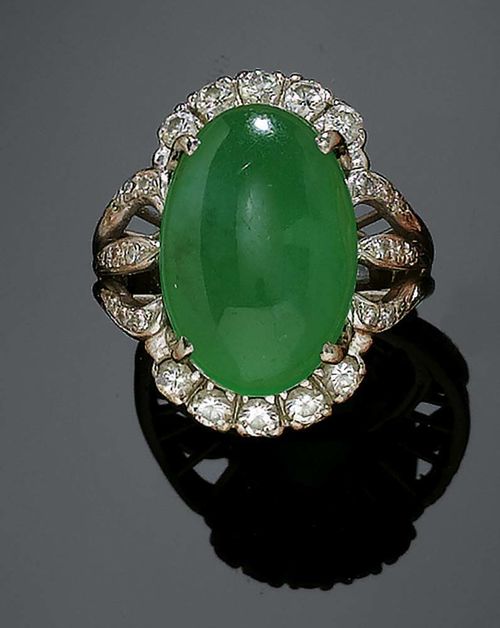 JADEITE AND DIAMOND RING, ca. 1950. White gold 750. Fancy ring, top set with 1 oval jadeite cabochon of ca 10.00 ct, surrounded by 10 brilliant-cut diamonds and flanked by 18 octagonal diamonds totalling ca 1.30 ct. Size ca. 44.5, with tension ring.