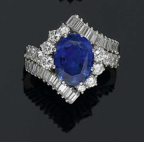 SAPPHIRE AND DIAMOND RING, BUCHERER, ca. 1975. Platinum 950. Elegant croisé ring, the top set with 1 oval sapphire of ca. 4.80 ct, surrounded by 22 diamond baguettes and 14 brilliant-cut diamonds, totalling ca. 2.10 ct. Size 59. With copy of insurance estimate from Bucherer, June 1975.