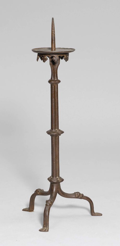 CANDLESTICK, France,in the Gothic style. Wrought iron. Large drip plates with cross-shaped decoration all around. Iron spike. On 3 feet decorated with heads of animals. H 44 cm.